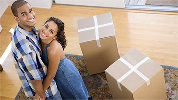 Smiling first time buyers with boxes in new home